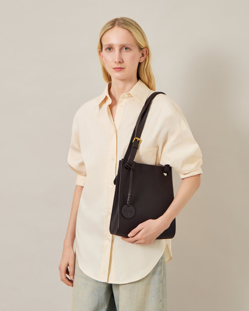 Mulberry Mini Soft Tote in dark brown Heavy Grain pebbled leather with adjustable flat crossbody strap, knotted corner attachments, and a tonal debossed tree logo charm on a leather tassel