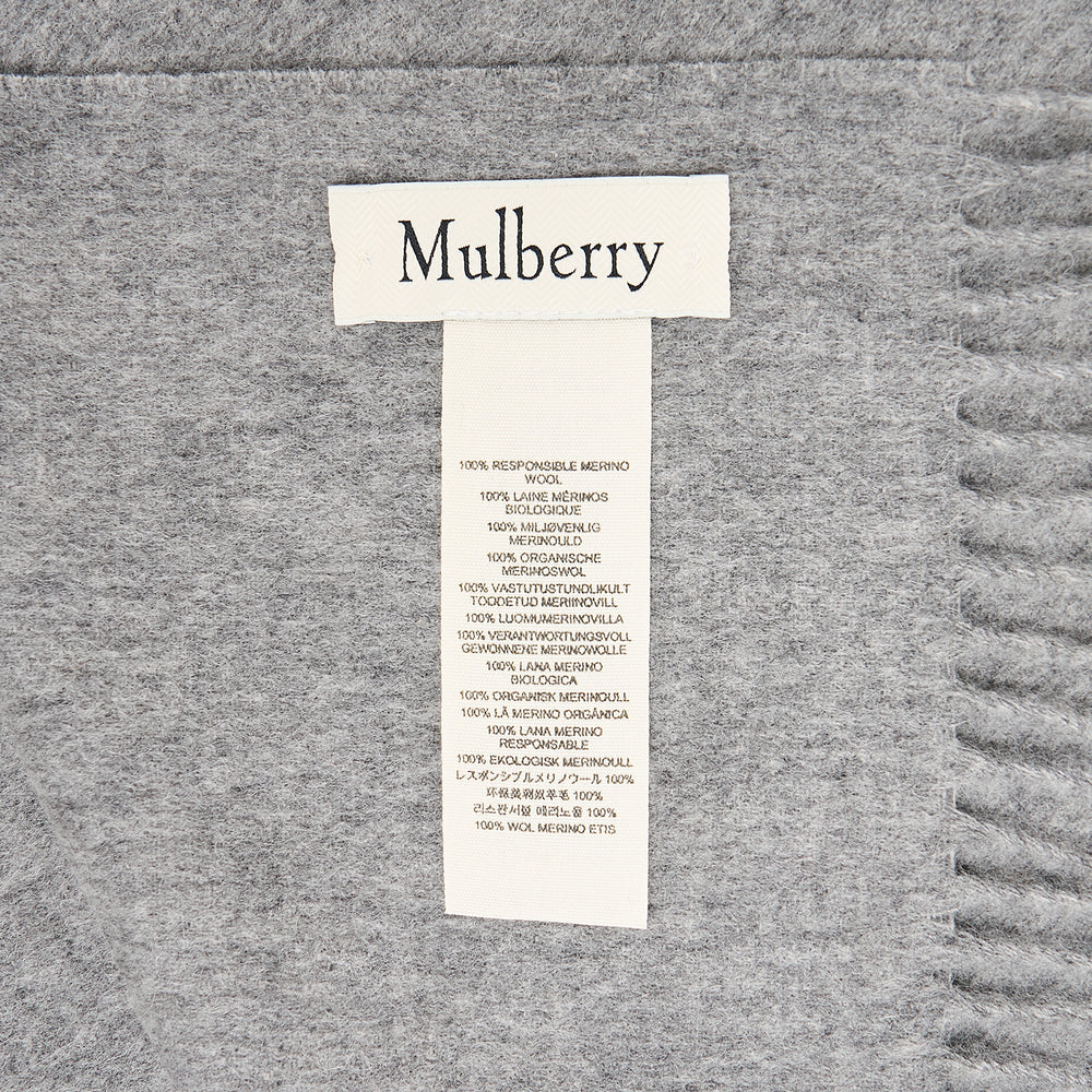 Mulberry Small Solid Merino Wool Scarf in tan with fringed ends and tonal embroidered branding, laid flat on a white background