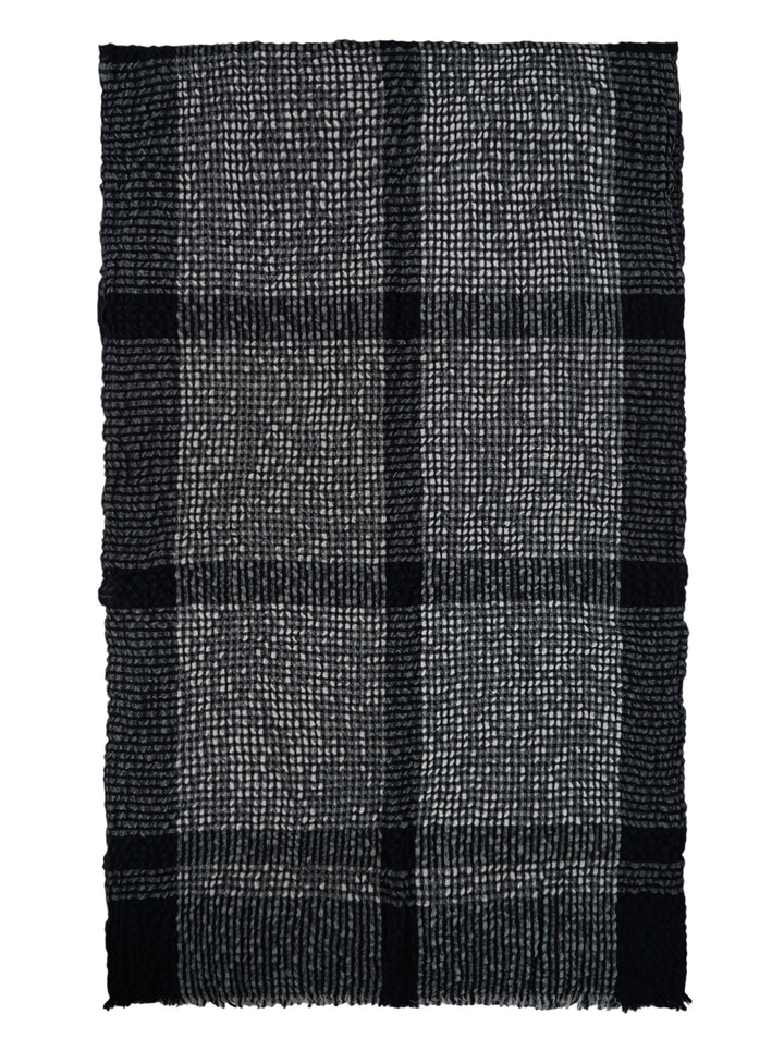 Issey Miyake Bumpy Wool Stole in monochrome black and grey check weave with dimensional textured surface, bold black stripe accents, and raw fringe hem edges