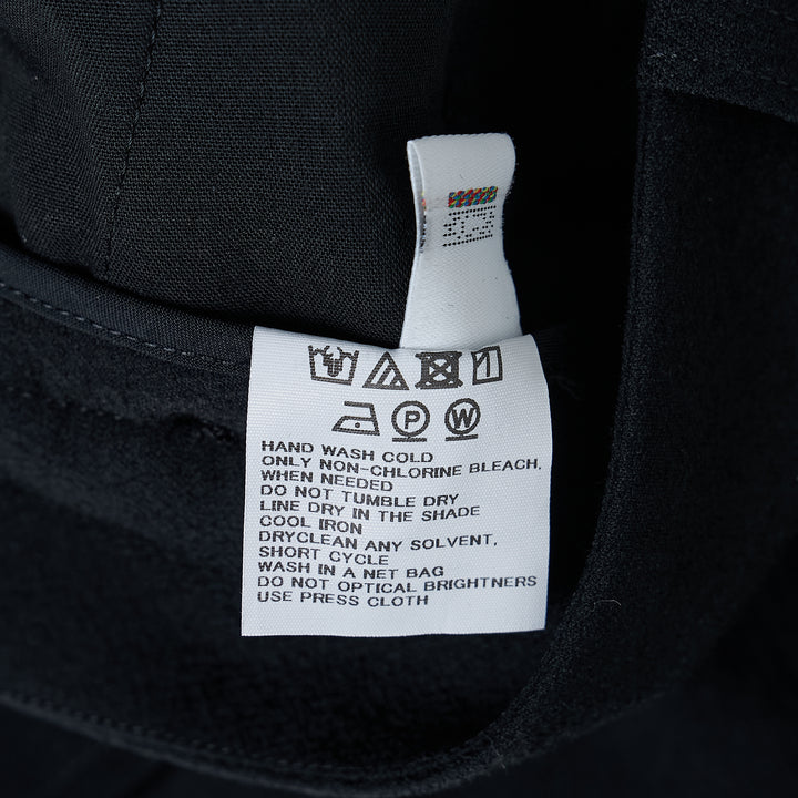 Issey Miyake Grainy Woven Flare Pants in black, flat lay front view showing flap pockets and flared leg silhouette