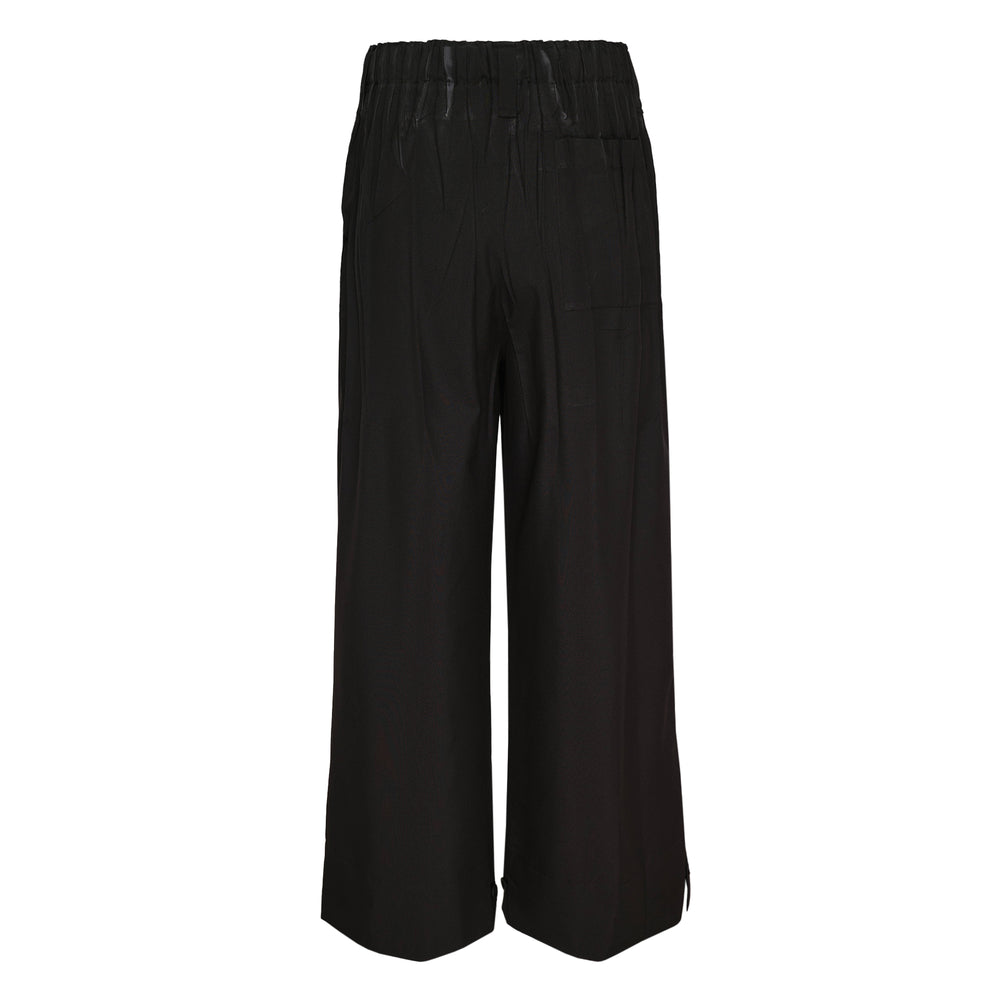 IM MEN Waft Black wide-leg woven pants with elasticated waistband, deep front pleats, and zip cuff detail, photographed flat on white background