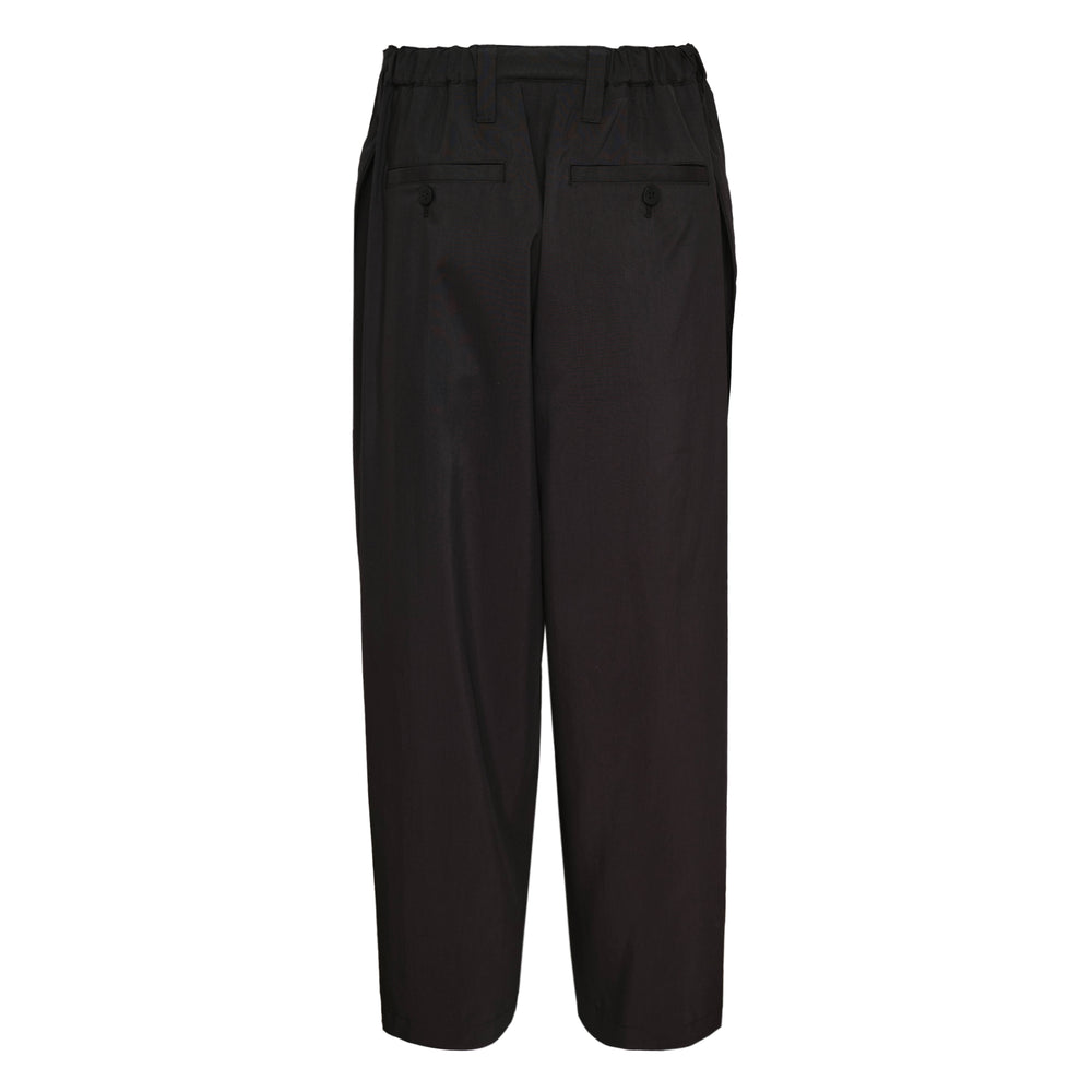 IM MEN Fluent Woven Pants in black, featuring a relaxed wide-leg silhouette, double front pleats, and a cropped hem, displayed flat on a white background