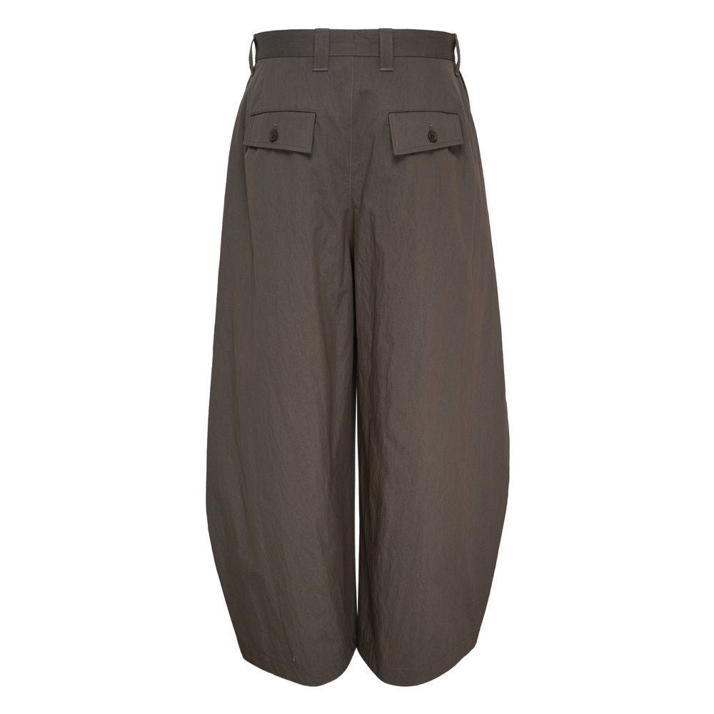 IM Men Overlap Woven Pants in taupe — high-rise wide-leg trousers with draped pleated overlay panels and a balloon-shaped cropped silhouette, front view on white background