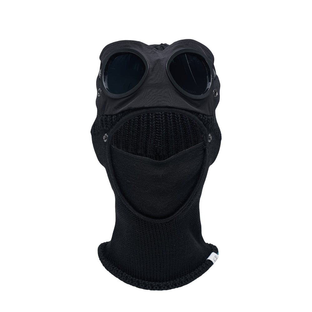 C.P. Company Extrafine Merino Wool Goggle Balaclava in black, displayed on a head form showing the ribbed knit construction and signature integrated circular goggle lenses with C.P. Company branding