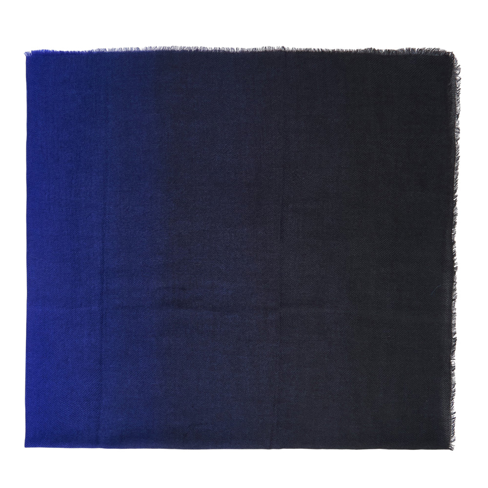 Faliero Sarti Coccola Sfumé square scarf laid flat, showing a horizontal ombré gradient from deep cobalt blue on one side fading to pale silvery blue, with fringe trim along all edges - view 2