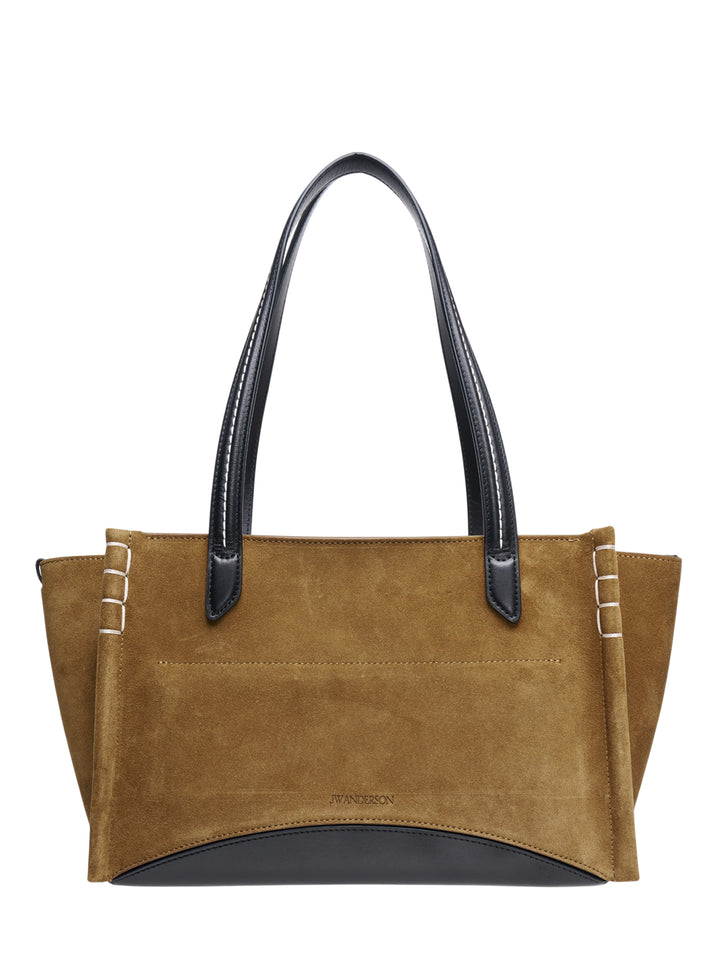JW Anderson Elongated Loafer Cabas tote bag in tan suede with black leather shoulder handles, curved leather base, and whipstitch gusset detailing