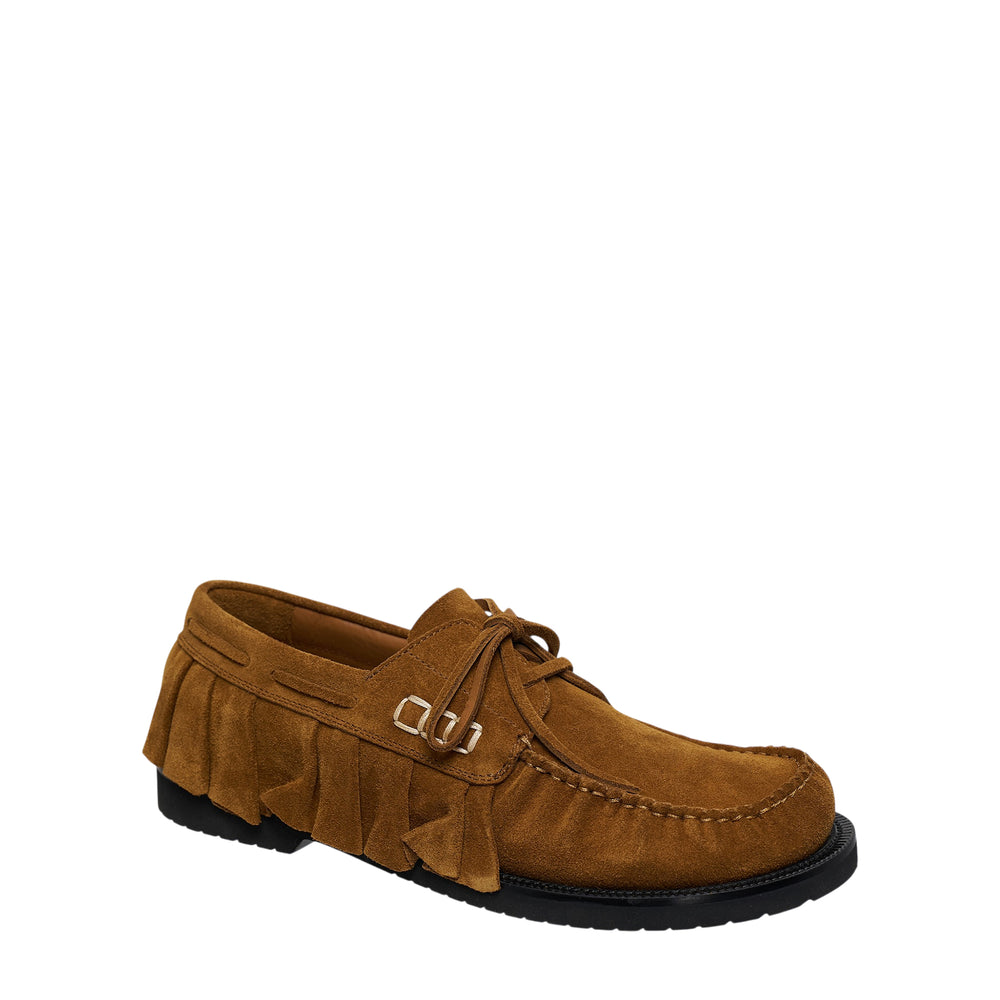 JW Anderson tan suede ruffle fringe boat loafer with kilt panels, metal buckle hardware, lace-up vamp, and black lug sole, shown in profile view
