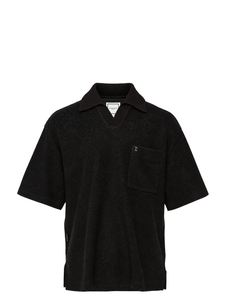 Wooyoungmi Oversized Textured Polo in black, featuring an open-placket collar, boxy short-sleeve silhouette, chest patch pocket with tonal WM monogram badge, and side hem vents
