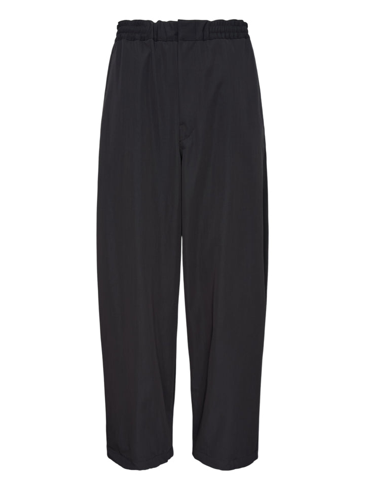 Lemaire black wool gabardine jogger pants with an elasticated waist and relaxed wide-leg silhouette, shown from the front