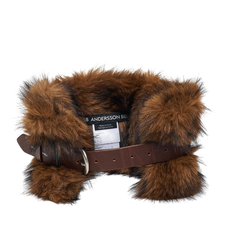 Andersson Bell Belted Fur Short Muffler in dark brown, featuring voluminous fur panels flanking a central brown leather belt strap with silver buckle, shown coiled and photographed flat against a white background