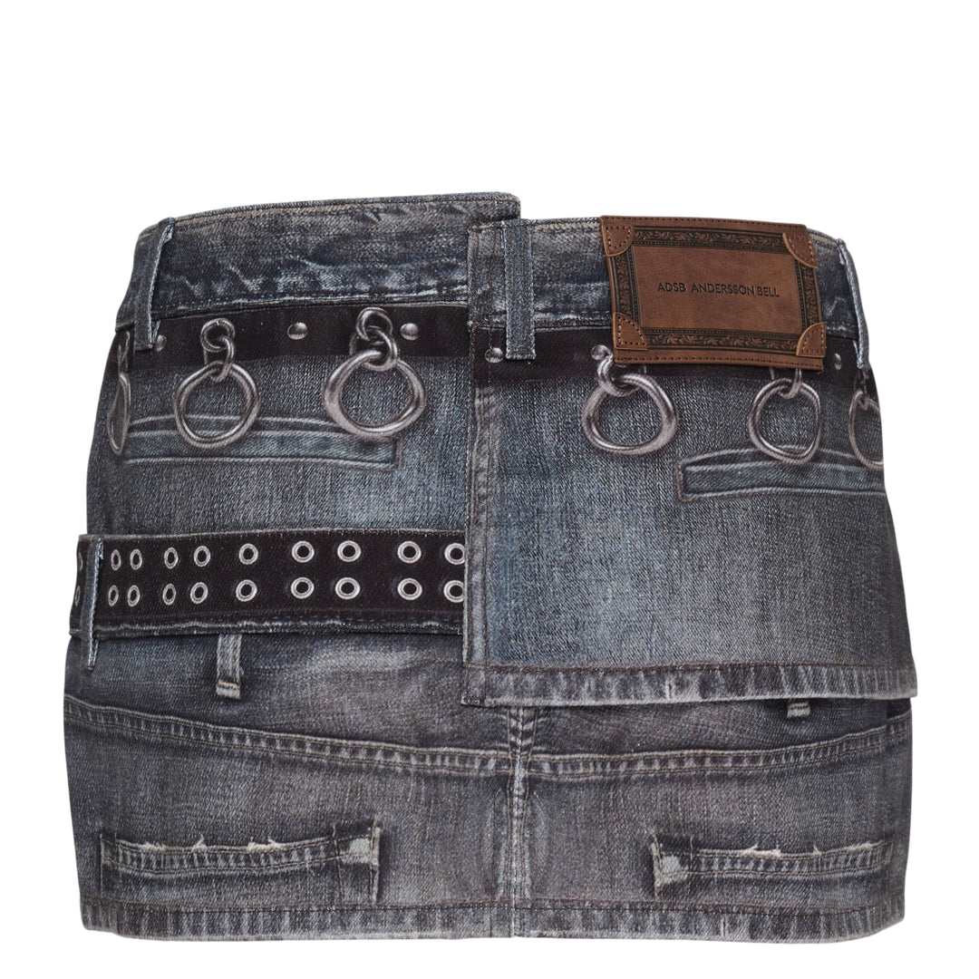 Andersson Bell Asymmetric Layered Wrap Skirt in washed indigo denim with studded belt straps, silver O-ring hardware, exposed zip, and contrast black layered hem