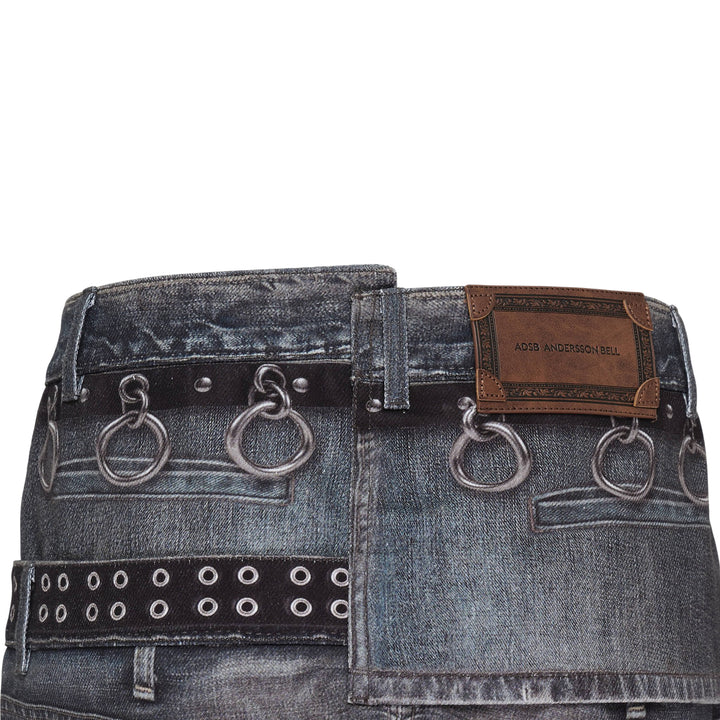 Andersson Bell Asymmetric Layered Wrap Skirt in washed indigo denim with studded belt straps, silver O-ring hardware, exposed zip, and contrast black layered hem