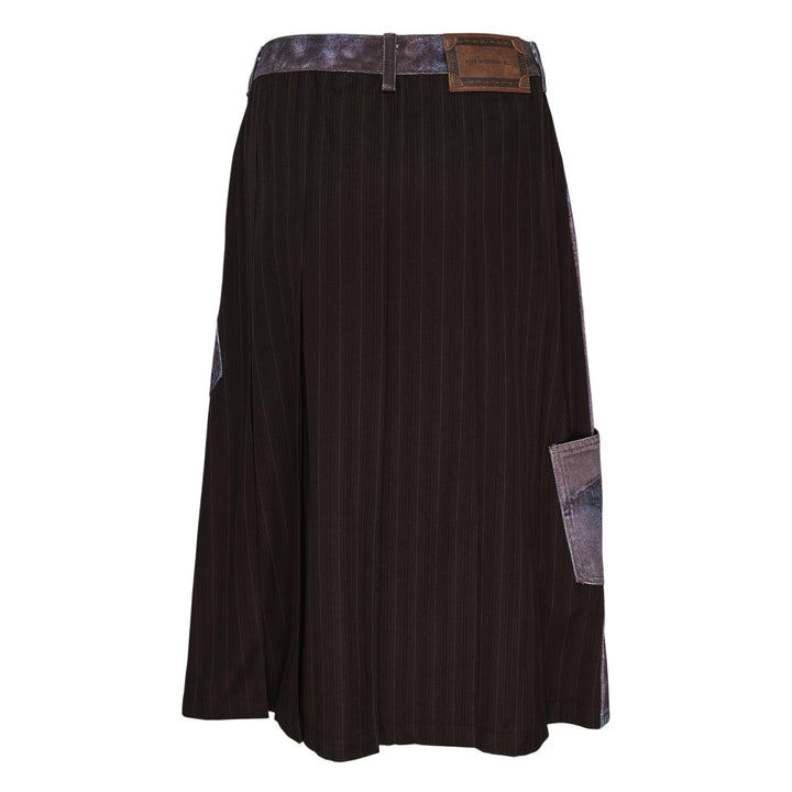 Andersson Bell Illusion Patchwork Denim Skirt with trompe l'œil patchwork print, high waist, silver-tone button closure, and pleated underlay hem on a white background