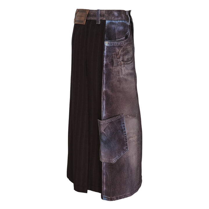 Andersson Bell Illusion Patchwork Denim Skirt with trompe l'œil patchwork print, high waist, silver-tone button closure, and pleated underlay hem on a white background
