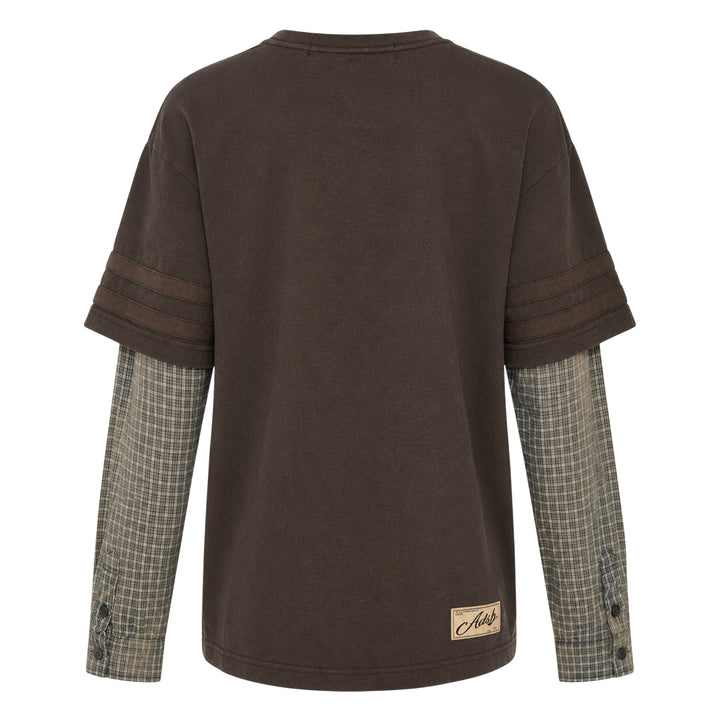 Andersson Bell Layered Sleeve Graphic Tee in washed dark jersey with tonal chest graphic print and green plaid shirting underlayer sleeves, shot flat on white background