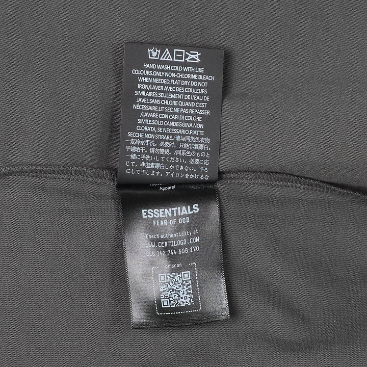 Fear of God Essentials Merch Tee in washed charcoal, featuring a boxy oversized silhouette, dropped shoulders, tonal chest branding patch, and a mock-neck collar