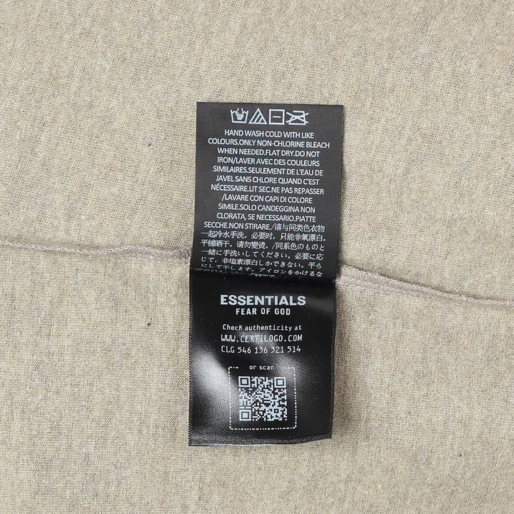 Fear of God Essentials Merch Tee in washed charcoal, featuring a boxy oversized silhouette, dropped shoulders, tonal chest branding patch, and a mock-neck collar