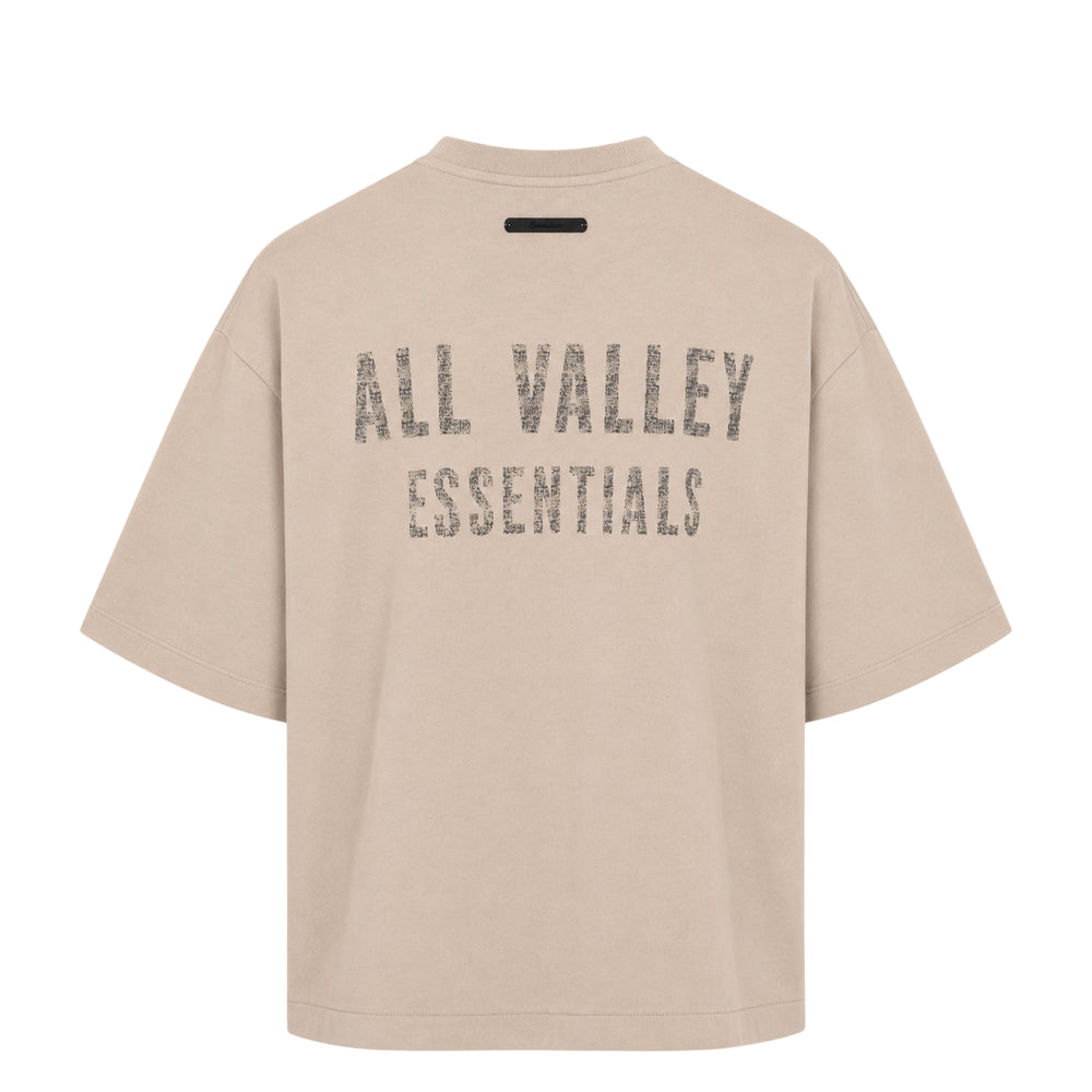 Fear of God Essentials Merch Tee in sage grey with tonal crystal-embellished 'Fear of God' wordmark across the chest, featuring a boxy oversized silhouette and mock-neck collar