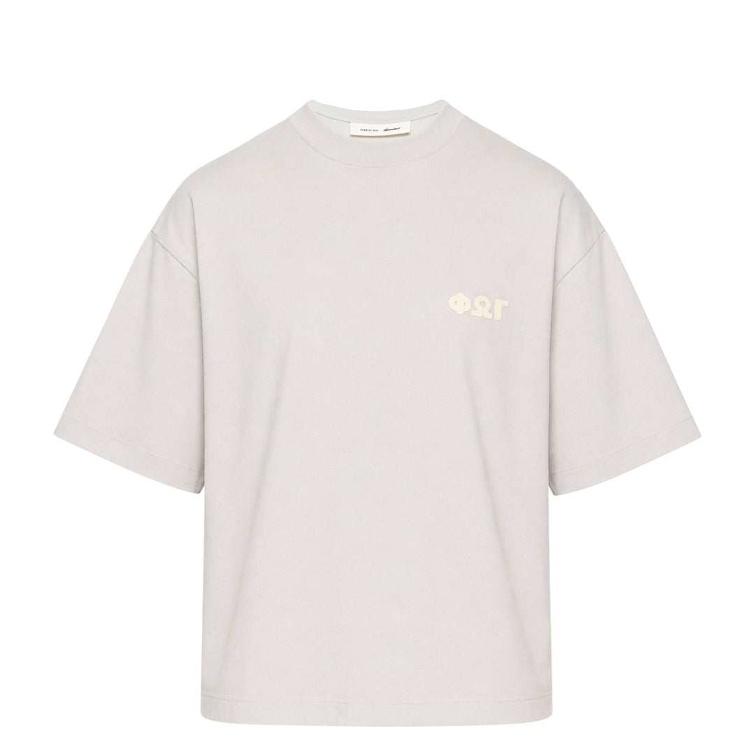Fear of God Essentials Merch Graphic Tee in blue-grey with tonal Greek-letter chest print, displayed flat on a white background