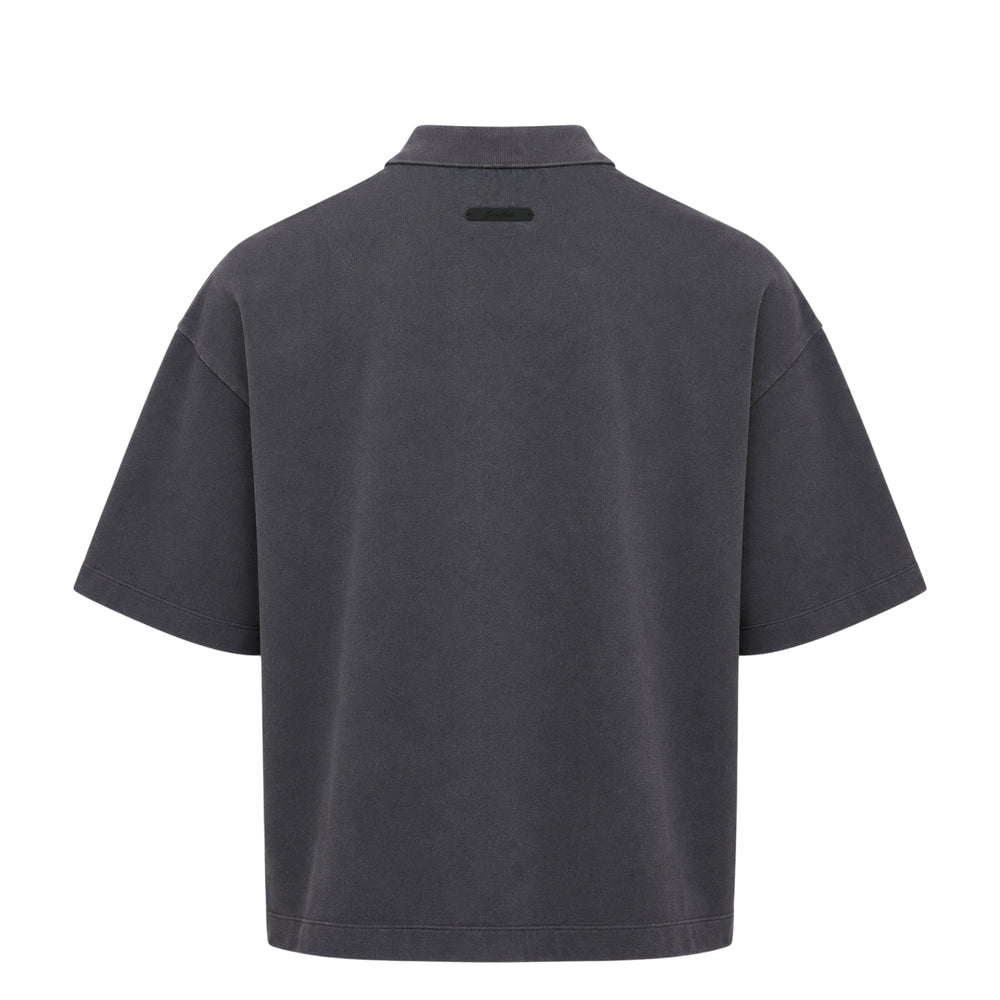 Fear of God Essentials F26 Cropped Polo in washed charcoal with tonal F26 puff-print branding on the chest, featuring a spread collar, concealed placket, and dropped-shoulder half sleeves
