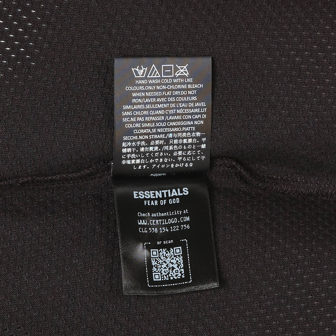 Fear of God Essentials All Valley Essentials Merch Tee in black, featuring a perforated mesh fabric, tonal arch graphic across the chest, and an oversized boxy silhouette with a ribbed mock-neck collar