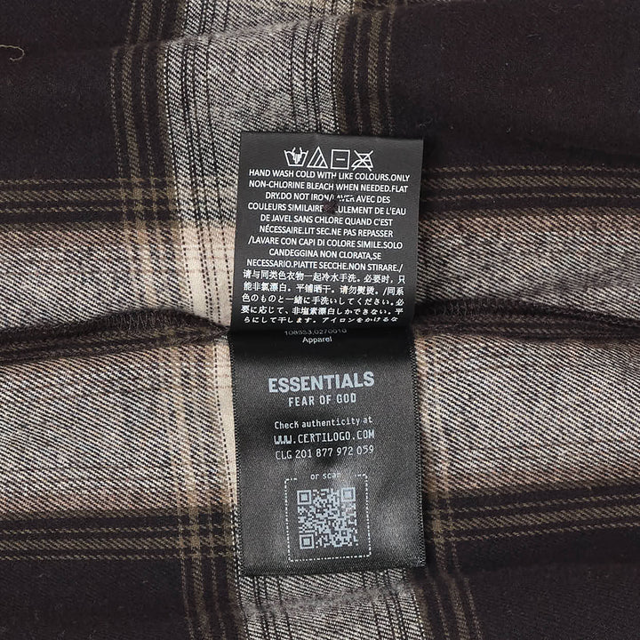 Fear of God Essentials long sleeve plaid button-up shirt in dark navy and grey windowpane check, relaxed oversized fit with concealed placket and tonal buttons, flat lay on white background