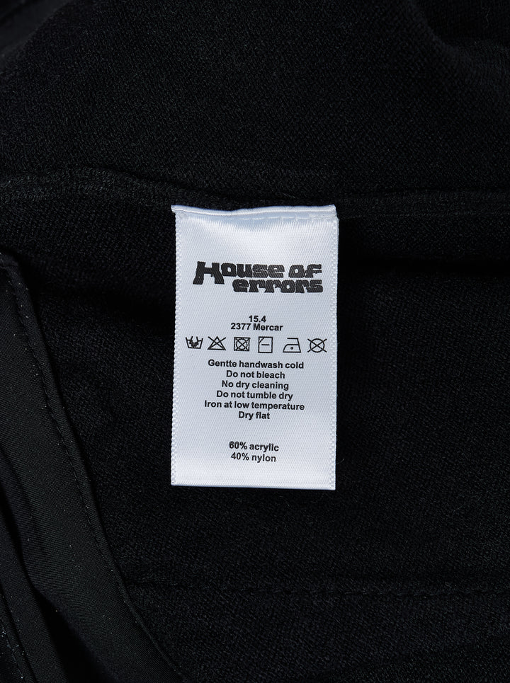 Black knitted pleated trousers with a high banded waist, button fastening and a small embroidered cat burglar motif at the hem - view 5
