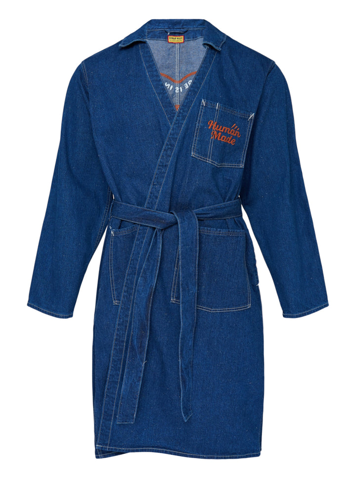 Human Made indigo denim work coat with wrap front, self-tie belt, patch pockets and orange embroidered logo on the chest pocket