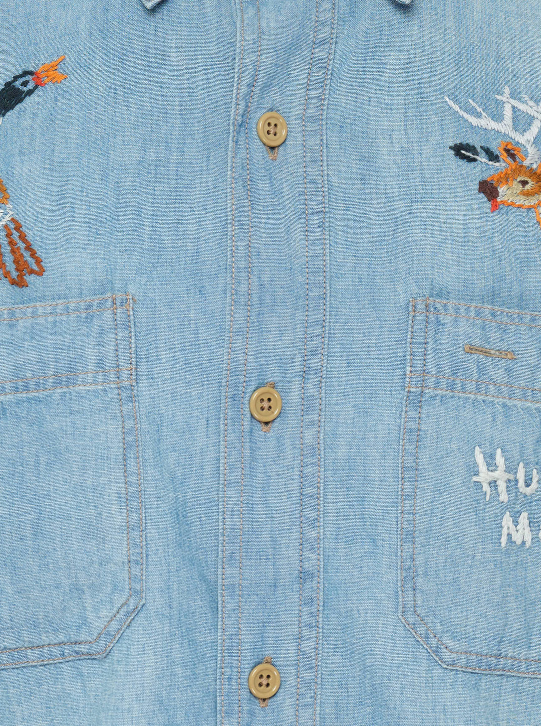 Human Made Embroidered Long Sleeve Chambray Shirt in light-wash denim, featuring a flying duck and deer head embroidery above dual chest pockets, with amber buttons and Human Made script embroidery - view 3