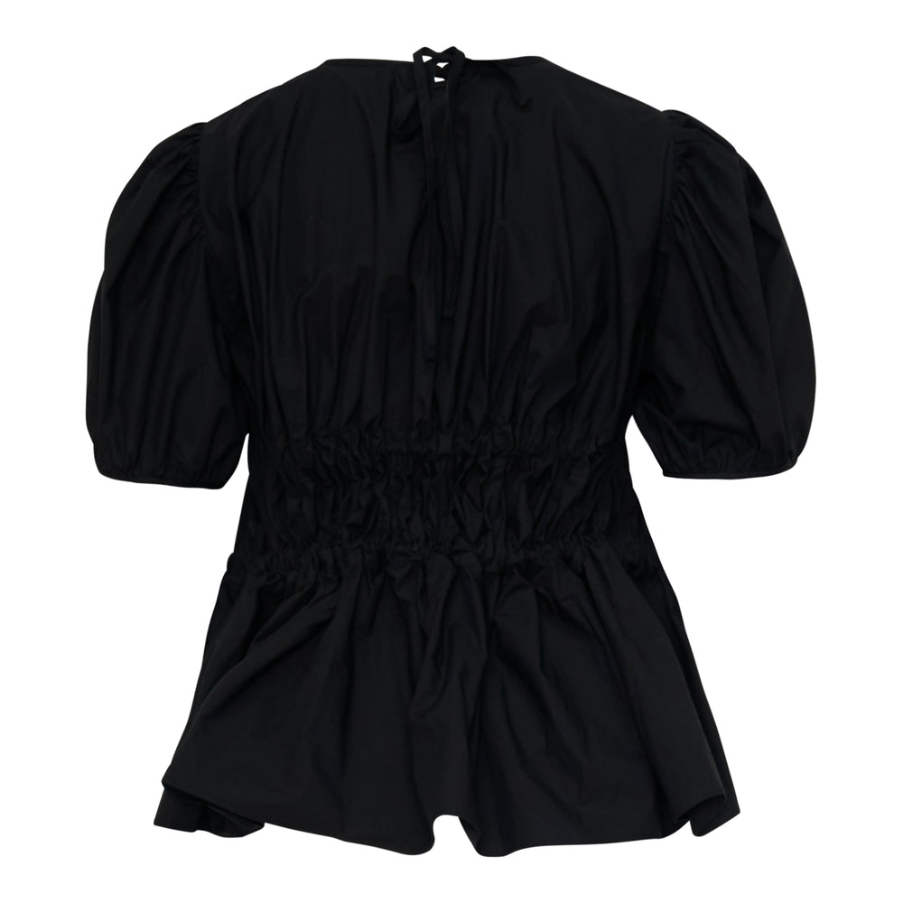 Cecilie Bahnsen Freya black cotton top with voluminous puff sleeves, smocked waist, grosgrain ribbon bow ties, and a peplum hem — back view on white background