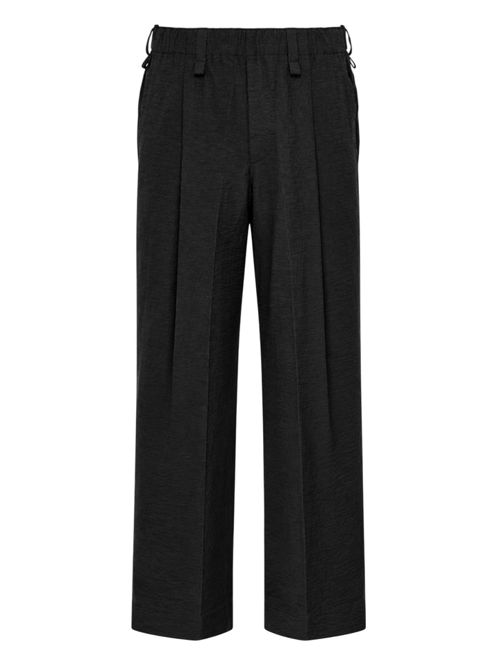 Homme Plissé Issey Miyake Opacity Woven Pants in black, flat lay showing wide-leg silhouette with front creases and elasticated drawstring waistband