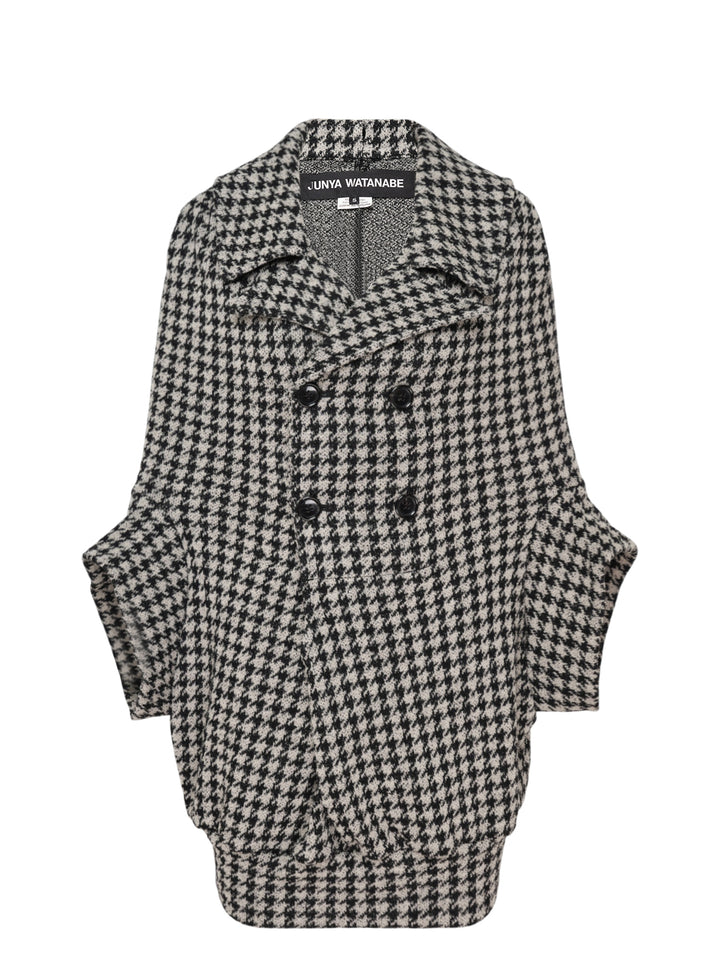 Junya Watanabe black and white houndstooth double-breasted structured coat with oversized silhouette, four black buttons, and large hip pockets, flat lay on white background