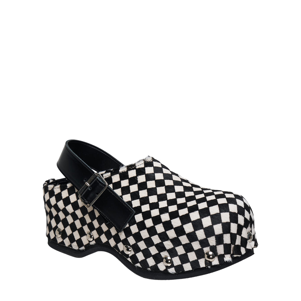 Tao checkerboard black and white hair calf platform clog with black leather ankle strap, silver buckle, and silver ball-stud trim along the chunky black sole