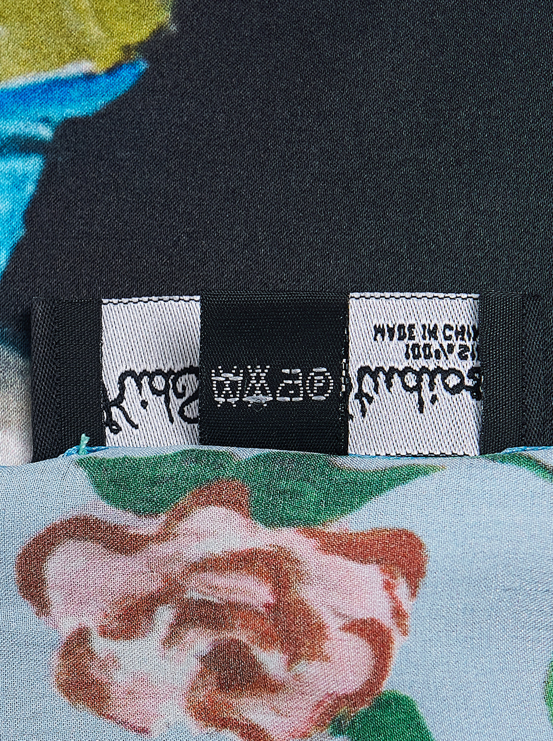 KidSuper Studios Puppet Master silk scarf featuring a painted marionette ballerina in a white and blue tutu on a black ground, framed by a blue border of red roses and script lettering - view 3