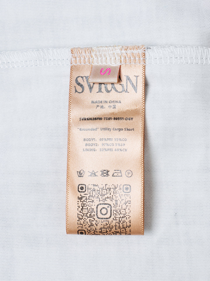 Sultry Virgin Utility Cargo Skort in grey suiting fabric, featuring a crossover wrap waistband with snap buttons, layered pleated panels, cargo pocket detailing, and a plaid underlay at the hem - view 3
