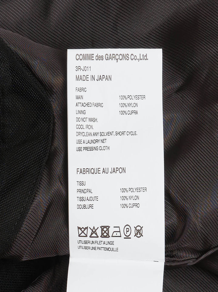 Noir Kei Ninomiya black oversized long sleeve jacket with high drawstring neck, silver zip closures, angled chest zip pockets, and layered black tulle ruffle hem, displayed flat on a white background - view 3