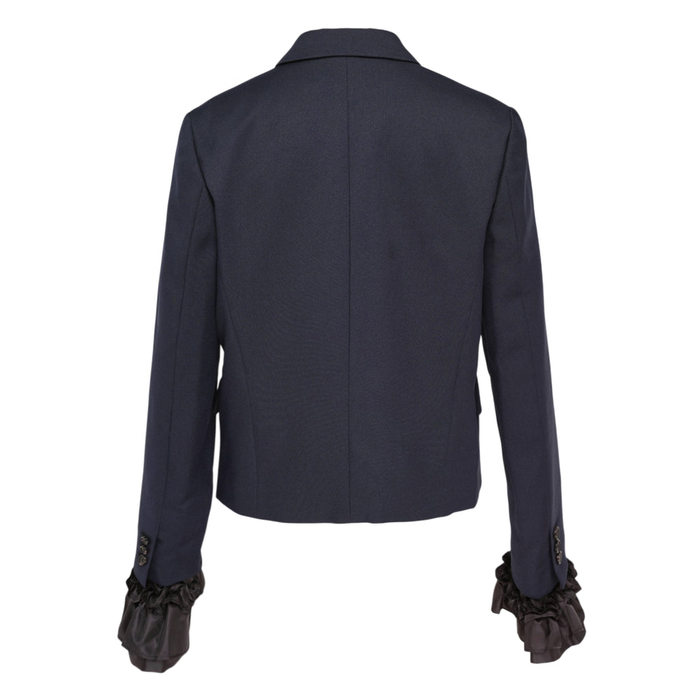 Comme des Garçons black tailored blazer with three-button front closure, notched lapels, and dramatic tiered sheer ruffle jellyfish hem and cuffs, displayed on a white background