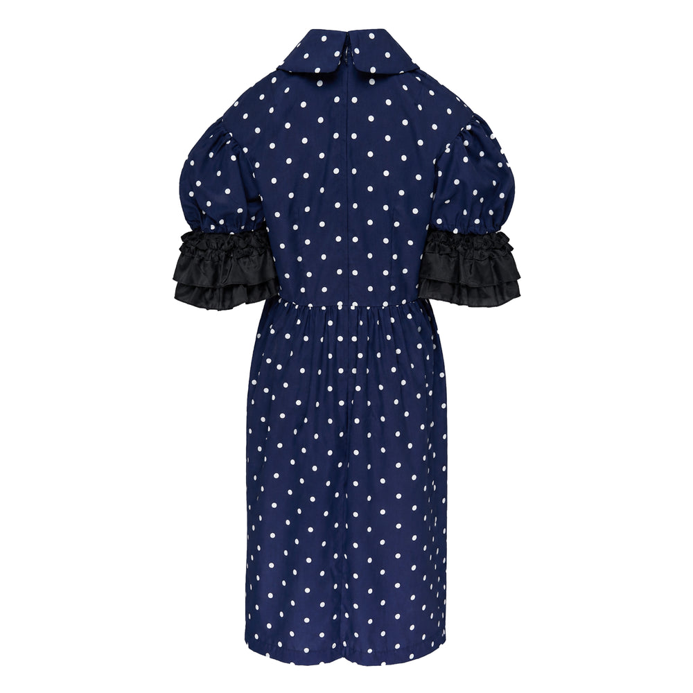 Comme des Garçons Girl oversized navy polka dot midi dress with Peter Pan collar, puff sleeves, and contrast black double-tiered ruffle cuffs, front view on white background