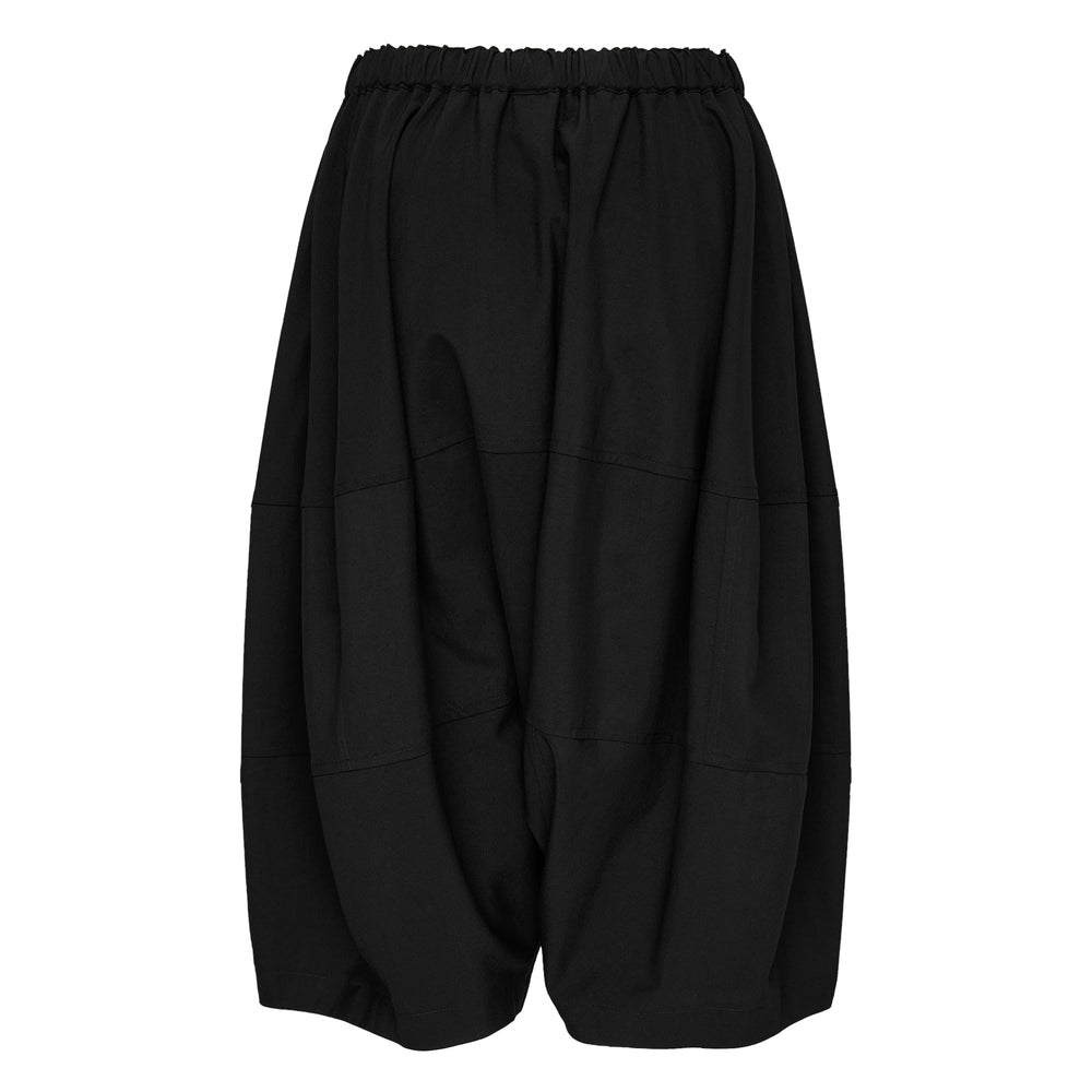 Comme des Garçons Girl black wide-leg relaxed pants with dropped crotch, horizontal panel seams, and elasticated gathered waistband, photographed flat on white background