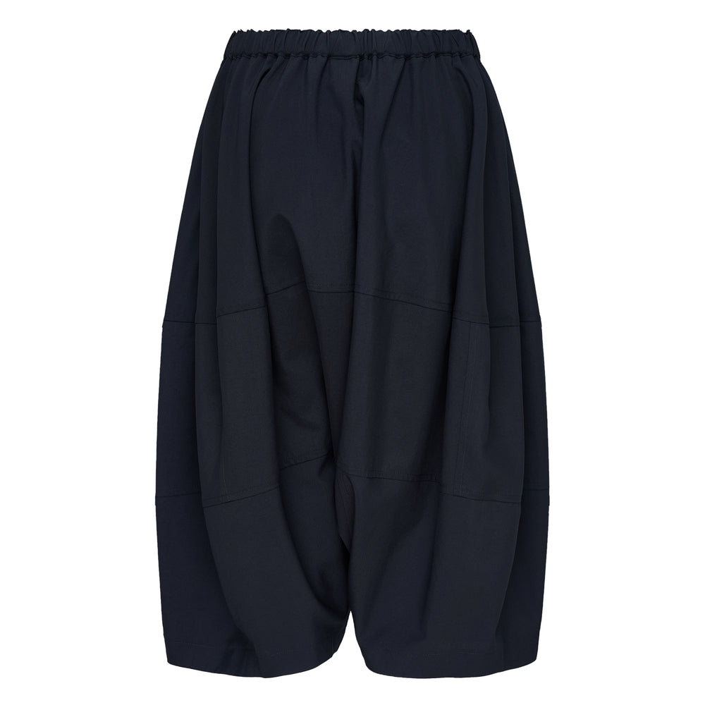 Comme des Garçons Girl black wide-leg relaxed pants with dropped crotch, horizontal panel seams, and elasticated gathered waistband, photographed flat on white background