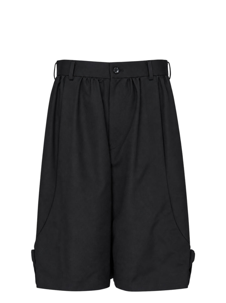 Comme des Garçons Girl black tailored knee-length shorts with wide-leg silhouette, soft pleating at the high-rise waistband, single-button closure, and cuffed hems