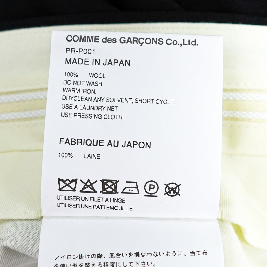 Comme des Garçons Homme Plus black wool tropical wide-leg pants with sculptural knotted bow and cascading ribbon hem trim, front view on white background - view 3
