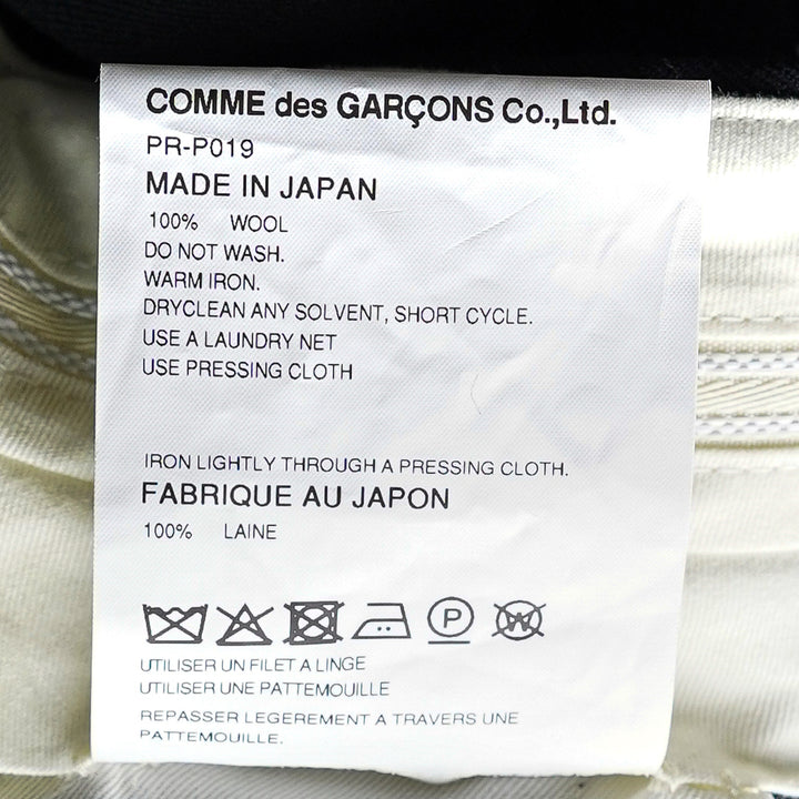 Comme des Garçons Homme Plus black double weave wool wide-leg shorts with deep pleats, button fly, and folded turn-up cuffs, shown flat on white background - view 3