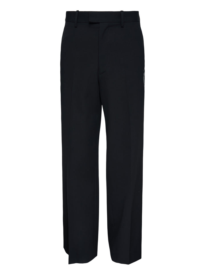 Undercover Cindy Sherman Patch Trousers in black, front view showing straight-leg tailored cut with pressed crease and patch detail