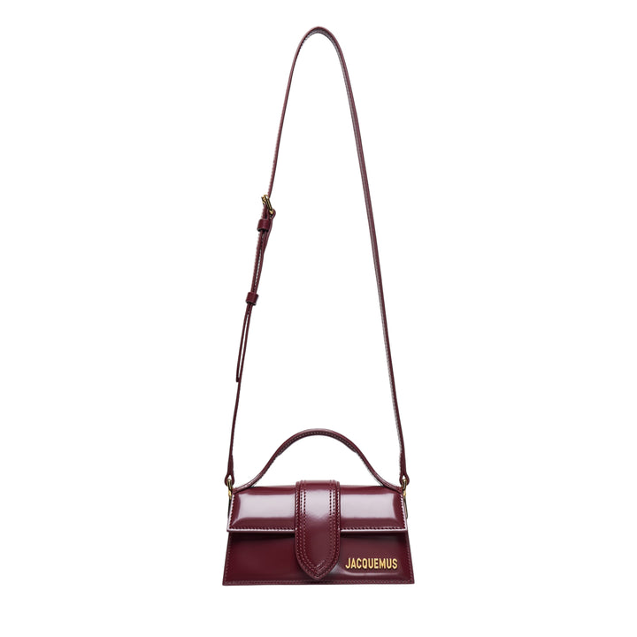Jacquemus Le Bambino Shiny mini shoulder bag in burgundy high-shine leather with gold logo lettering, top handle, and adjustable crossbody strap