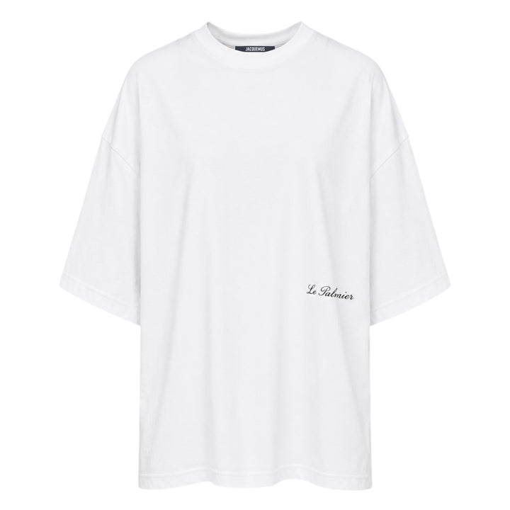Jacquemus Le Palmier oversized white cotton tee with drop shoulders and 'Le Palmier' script embroidery at the hem, product flat lay