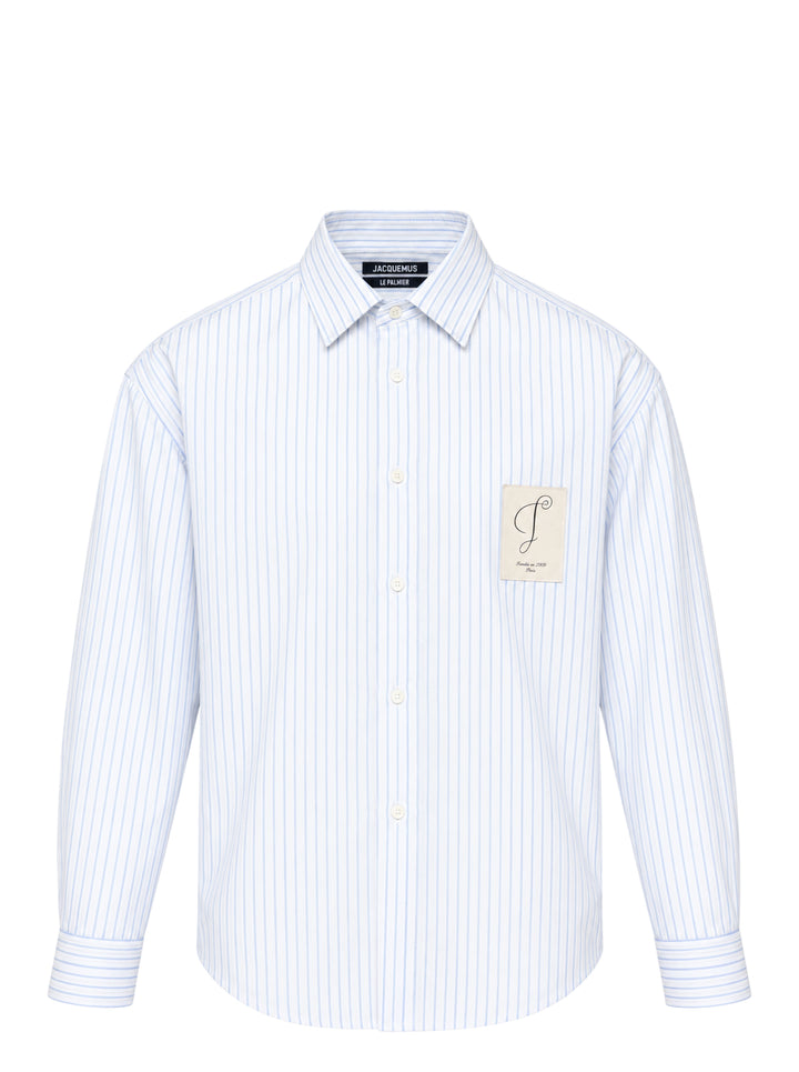 Jacquemus Simon long sleeve shirt in blue and white pinstripe with a script 'J' patch on the chest