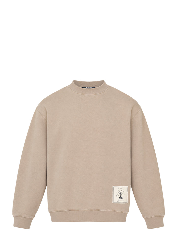Jacquemus Torneo sweatshirt in taupe with ribbed mock neck and a Le Palmier palm illustration label at the hem