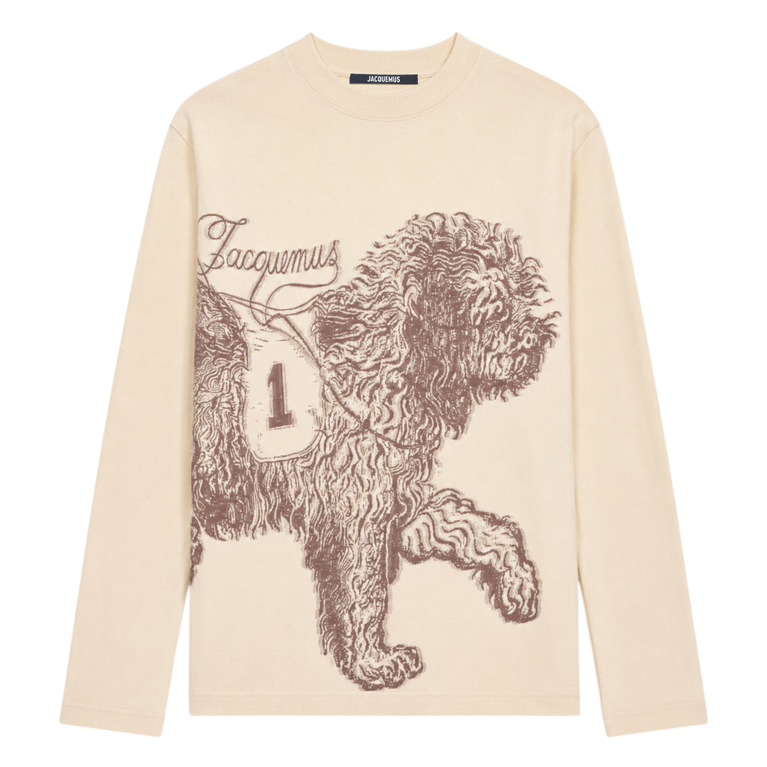 Jacquemus Le T-Shirt Bichon in ecru — long-sleeve crew-neck tee featuring a tonal brown hand-drawn curly dog illustration with a varsity number bib and cursive Jacquemus script across the front