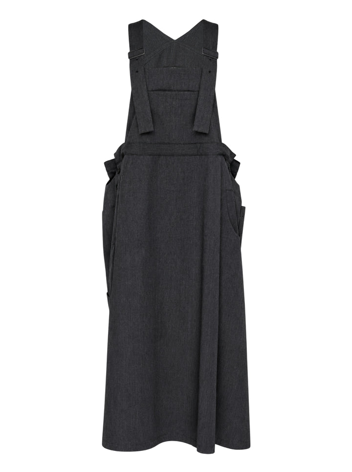 Y's charcoal grey wool salopette dress with crossover bib, buckled straps and oversized side pockets, shown from the front